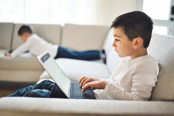 Enfants relaxants avec leurs tablettes sur un canapé confortable à la maison — Photo