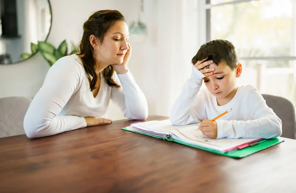 Мати викладає нудного сина і допомагає з домашнім завданням вдома — стокове фото