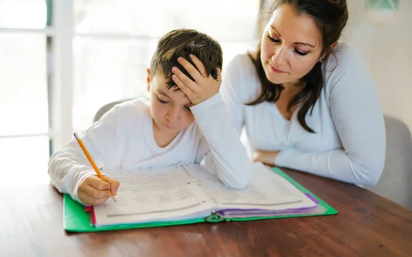 Moeder onderwijs verveelde zoon en helpen met huiswerk thuis — Stockfoto
