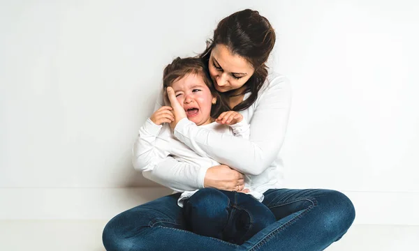 Мати втішає свою дівчинку плачуть на білому — стокове фото
