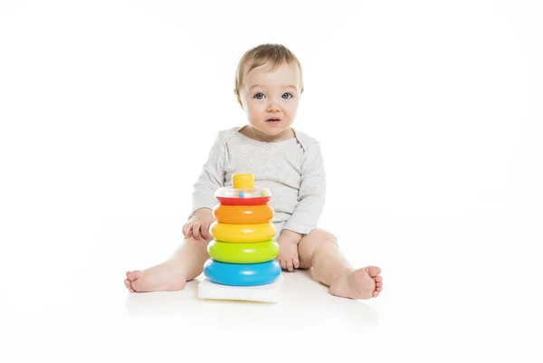 Baby girl sitting on floor playing with toy isolated on white background. — Stockfoto