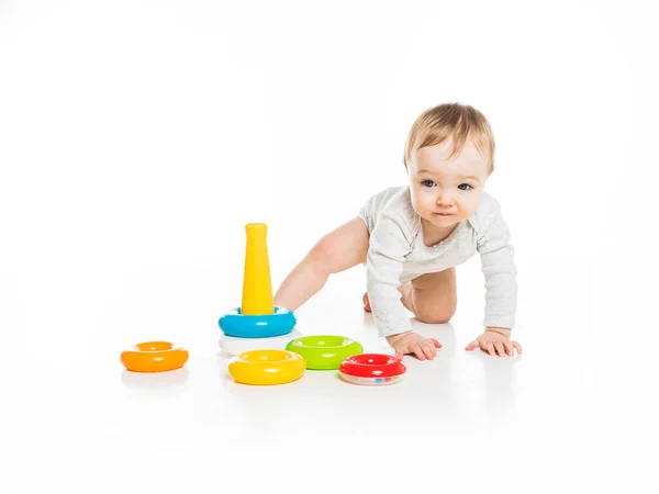 Baby flicka på golvet leka med färg leksak isolerad på vit bakgrund. — Stockfoto