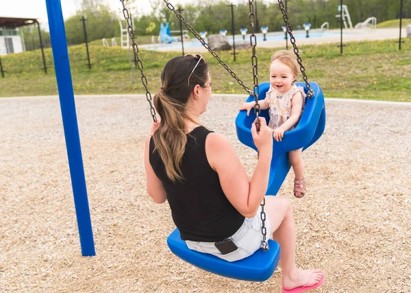 Linda niña jugando en el patio al aire libre con la madre en swing —  Fotos de Stock