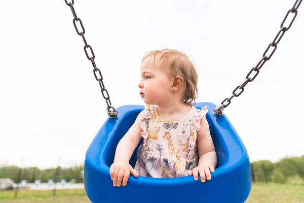 Cute baby girl playing on outdoor swing playground — Stock fotografie