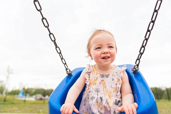 Söt liten flicka leker på utomhus swing lekplats — Stockfoto