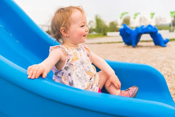 Cute baby girl playing on outdoor slide playground — Stock Fotó