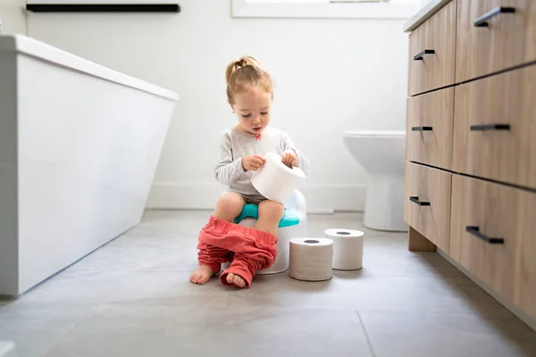 Adorable young baby child sitting and learning how to use the toilet with toilet paper on hand — Photo