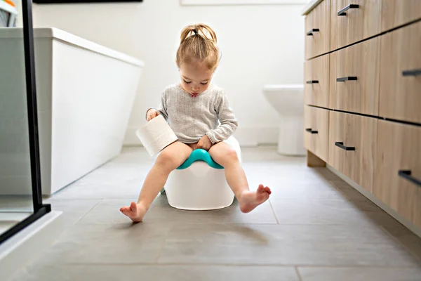 Adorable jeune enfant assis et apprenant à utiliser les toilettes avec du papier toilette à portée de main — Photo