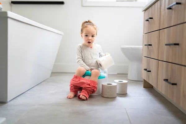 Adorable young baby child sitting and learning how to use the toilet with toilet paper on hand — Photo