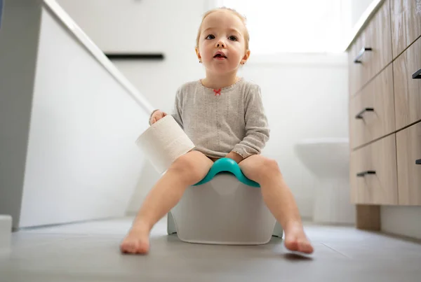 Adorabile bambino seduto e imparare a usare la toilette con la carta igienica a portata di mano — Foto Stock
