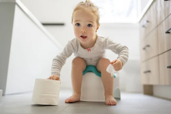 Adorable young baby child sitting and learning how to use the toilet with toilet paper on hand — Stock Photo, Image