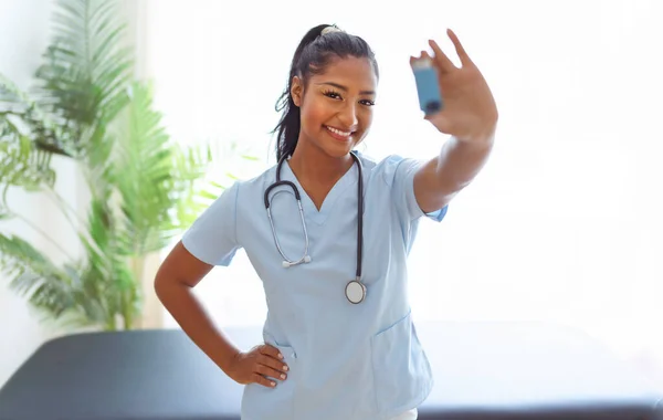 Young doctor holding asthma inhaler in clinic — Stock Photo, Image