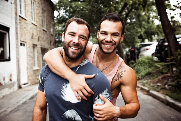 Ett porträtt av ett lyckligt homosexuellt par utomhus i urban bakgrund — Stockfoto