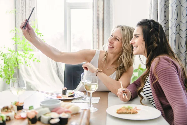 Two attractive mature people eating sushi at home taking photo — Stock Photo, Image