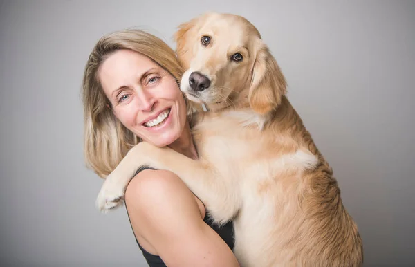 Nice woman and her beautiful Golden Retriever dog over gray background — Stockfoto