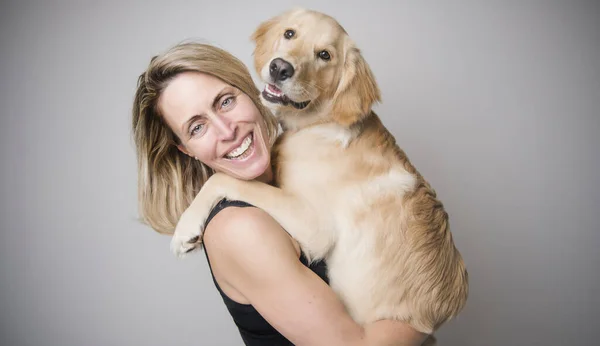 Nice woman and her beautiful Golden Retriever dog over gray background — Stockfoto