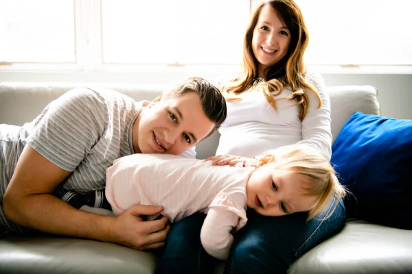 A Beautiful pregnant mother and father with her children girl at the living room — ストック写真