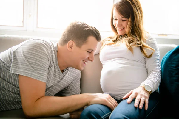 Šťastný muž s těhotnou ženou sedící na gauči — Stock fotografie