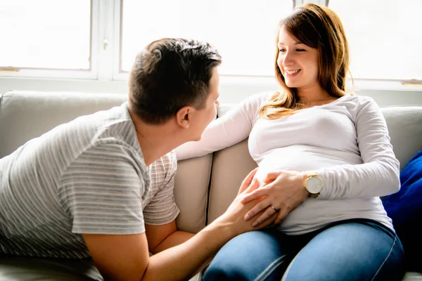 A happy man with pregnant woman sitting on couch — Fotografia de Stock