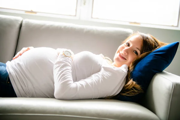 幸せな妊婦は自宅でソファに横たわっています — ストック写真