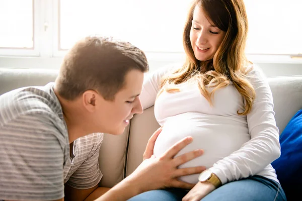 A happy man with pregnant woman sitting on couch — Stockfoto
