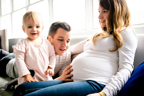 A Beautiful pregnant mother and father with her children girl at the living room — Stock Photo, Image
