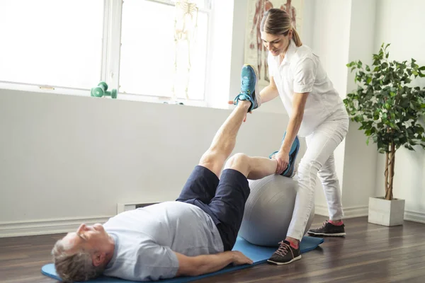 Um trabalhador de fisioterapia de reabilitação moderna com cliente sênior — Fotografia de Stock