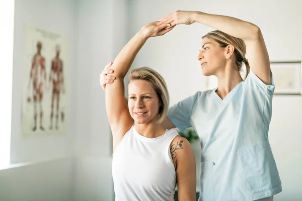 Een moderne revalidatie fysiotherapeut werknemer met vrouw cliënt — Stockfoto