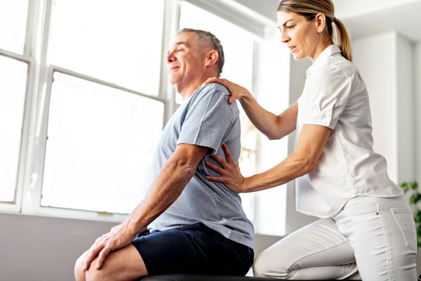 Ein moderner Reha-Physiotherapeut mit Seniorenkunden — Stockfoto
