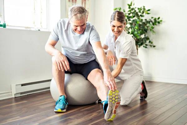 En modern rehabilitering sjukgymnast arbetare med senior klient — Stockfoto