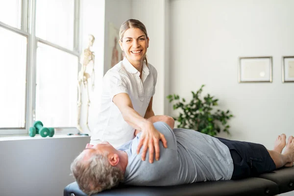Un moderno fisioterapeuta de rehabilitación con cliente senior — Foto de Stock