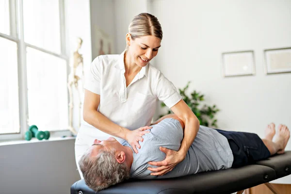Un travailleur en physiothérapie de réadaptation moderne avec un client aîné — Photo