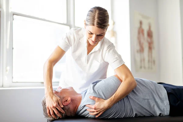 Um trabalhador de fisioterapia de reabilitação moderna com cliente sênior — Fotografia de Stock