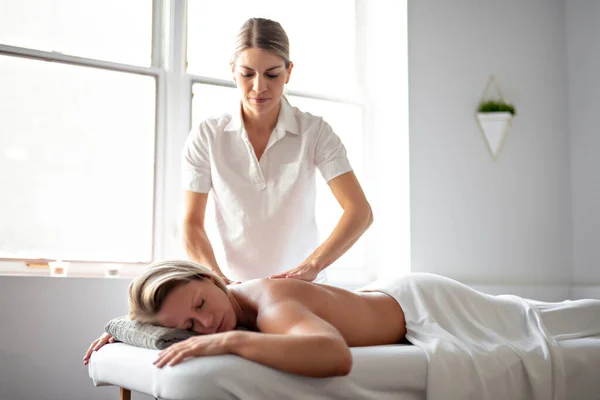 Een vrouw genieten van spa behandeling in salon met masseur werknemer — Stockfoto