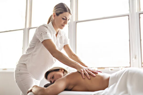 Una mujer disfrutando de un tratamiento de spa en el salón con masajista — Foto de Stock