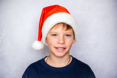 Noel ve yeni yıl tatillerinde Noel Baba şapkası takan mutlu küçük çocuk.