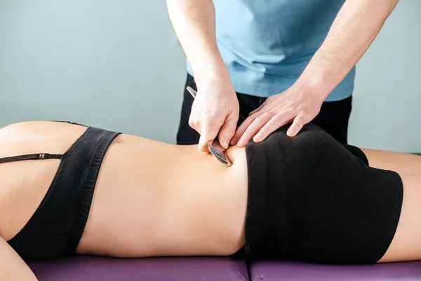 Physical therapist fixing sacroiliac joint pain with IASTM guasha tool
