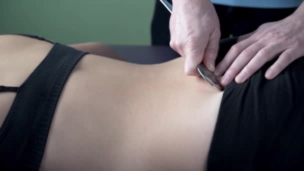 Физиотерапевт фиксирует боль в крестцово-подвздошных суставах инструментом гуаши IASTM — стоковое видео