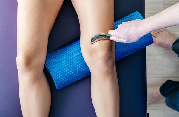 Osteopat diz kapağı Patellofemoral ağrı sendromunu tedavi etmek için IASTM tekniği uyguluyor.