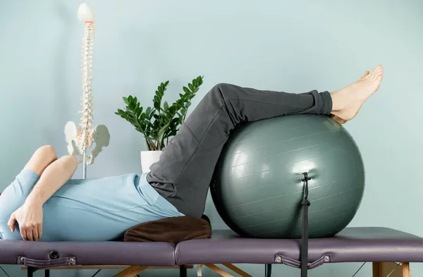 Um homem deitado na mesa de massagem em posição de descanso construtivo, si alívio da dor nas articulações — Fotografia de Stock