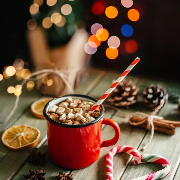 Kırmızı emaye bardakta sıcak çikolata ve Noel arkaplanında lokum.
