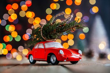 Noel ağaçları arka plan dağıtır, köknar ağacıyla kırmızı oyuncak araba renkli Noel ışıklarına karşı bokeh