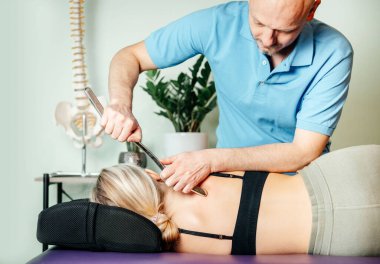 Chiropractor performing myofascial release techniques with IASTM tool for the Rhomboids clipart