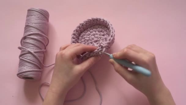 Tangan wanita memegang tongkat pengait dan benang warna merah muda pada latar belakang merah muda, merajut dan crochet persediaan — Stok Video