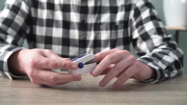 Een man die het zuurstofgehalte thuis controleert met een thuisoximeter, een patiënt die de bloedzuurstof meet met een oximeter — Stockvideo