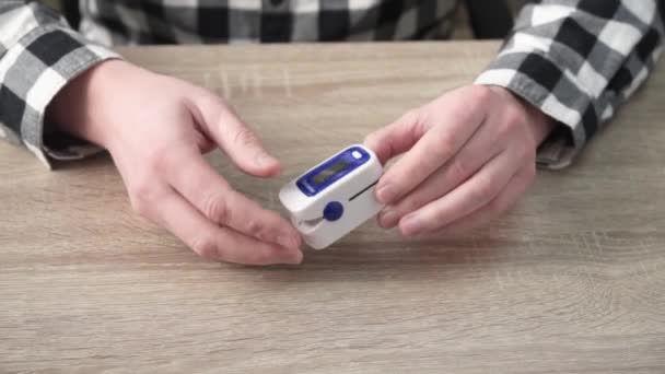 Een man die het zuurstofgehalte thuis controleert met een thuisoximeter, een patiënt die de bloedzuurstof meet met een oximeter — Stockvideo