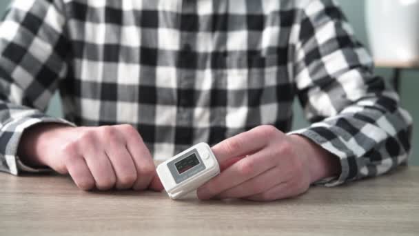 Een man die het zuurstofgehalte thuis controleert met een thuisoximeter, een patiënt die de bloedzuurstof meet met een oximeter — Stockvideo