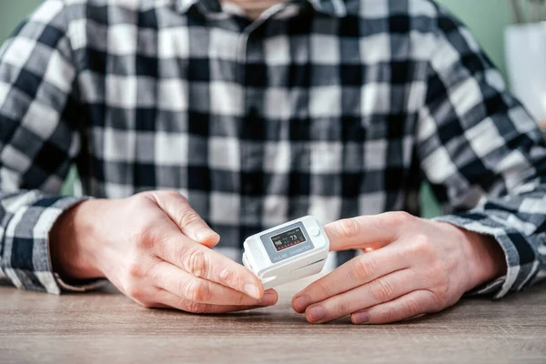 Un homme vérifiant le niveau d'oxygène à la maison avec un oxymètre à domicile, patient mesurant l'oxygène sanguin avec un oxymètre — Photo