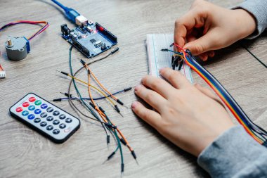 Arduino kodlama ve robotik öğrenirken algılayıcı çiplerine kablo takan bir çocuk