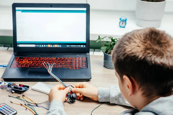 Een jongen pluggen kabels naar sensor chips tijdens het leren van arduino codering en robotica — Stockfoto
